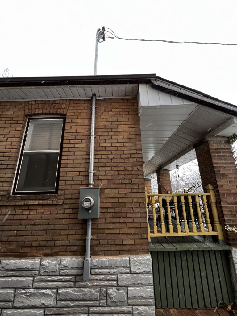 Electrical meter and service mast installed on a brick home