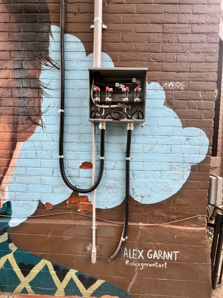 Dual meter-base installation and conduit on a painted exterior brick wall