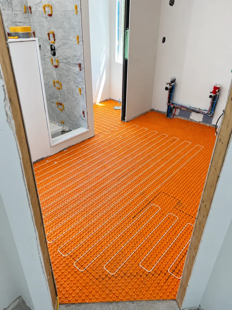 Electric heating cable laid in an orange uncoupling membrane during a bathroom renovation
