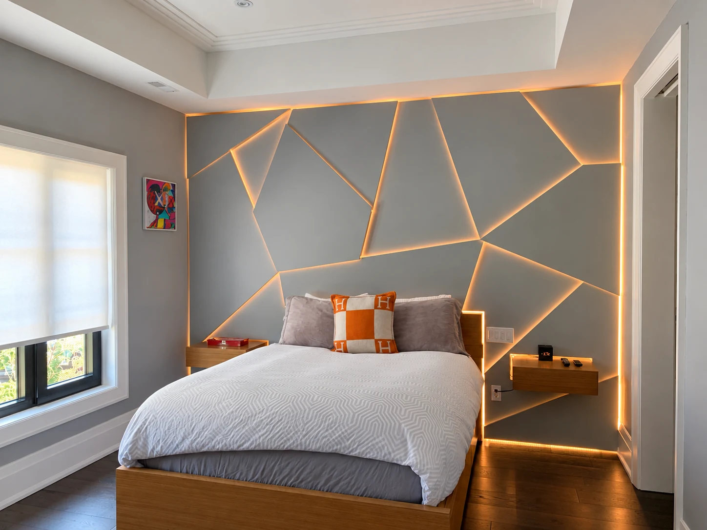 Bedroom with warm concealed LED lighting outlining geometric wall panels, headboard and floating bedside tables