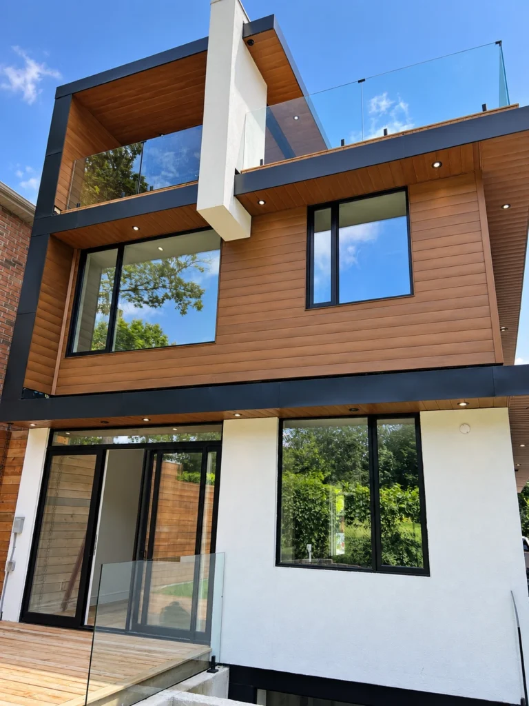 Modern custom home with recessed soffit lighting, wood cladding and glass balcony railings