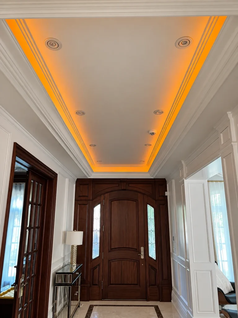 Entryway with concealed amber cove lighting, recessed ceiling fixtures and a ceiling-mounted smoke detector