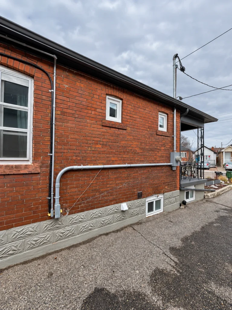 Electrical meter and surface-mounted service conduits on a red brick house