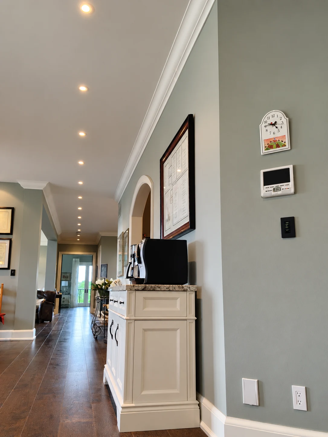 Row of recessed hallway lights beside a coffee cabinet and wall-mounted controls