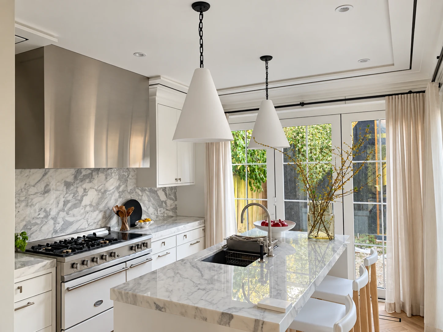Two white cone pendants over a marble kitchen island