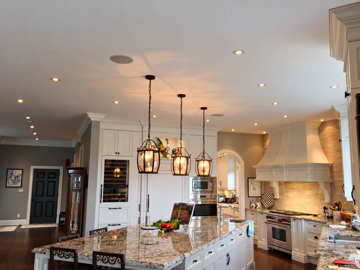 Three lantern pendants and recessed lights above a traditional kitchen island