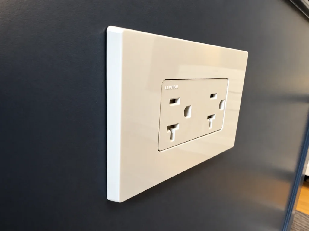White Leviton duplex receptacle mounted horizontally in a screwless wall plate on a charcoal wall