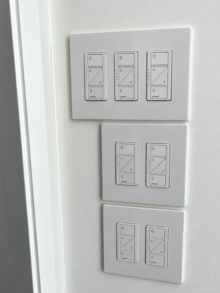 Seven white Lutron lighting dimmers arranged in three screwless wall plates