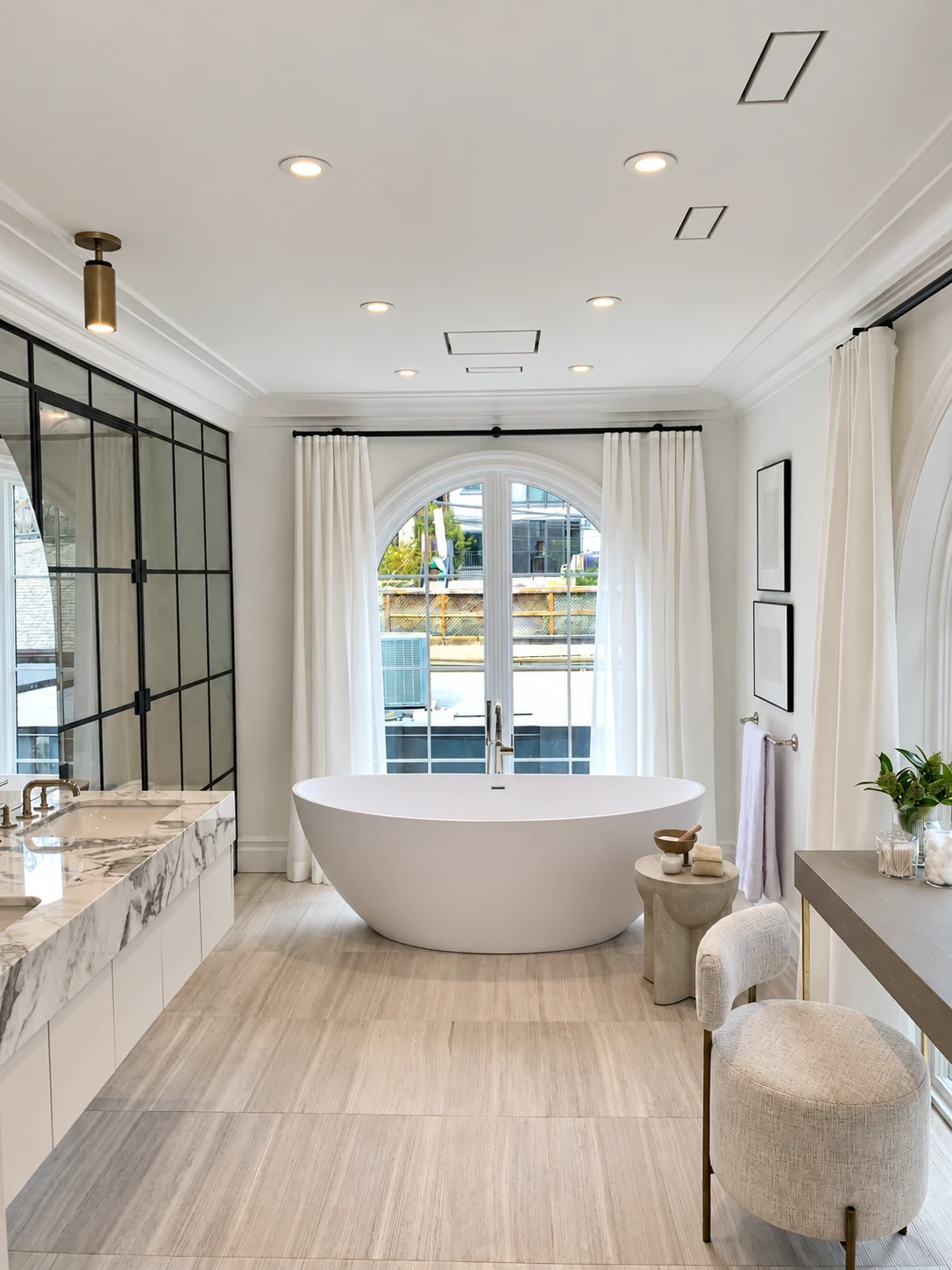 Recessed ceiling lights and a brass cylinder fixture in a bathroom with a freestanding tub