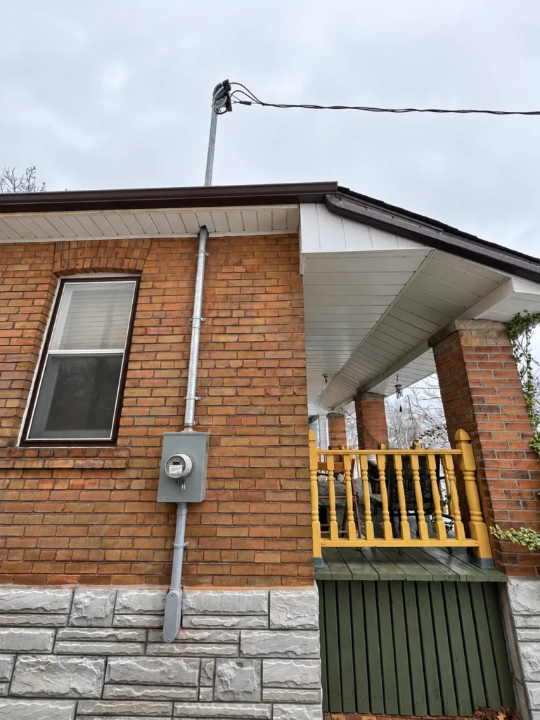 Residential overhead electrical service mast and electricity meter mounted on a brick home