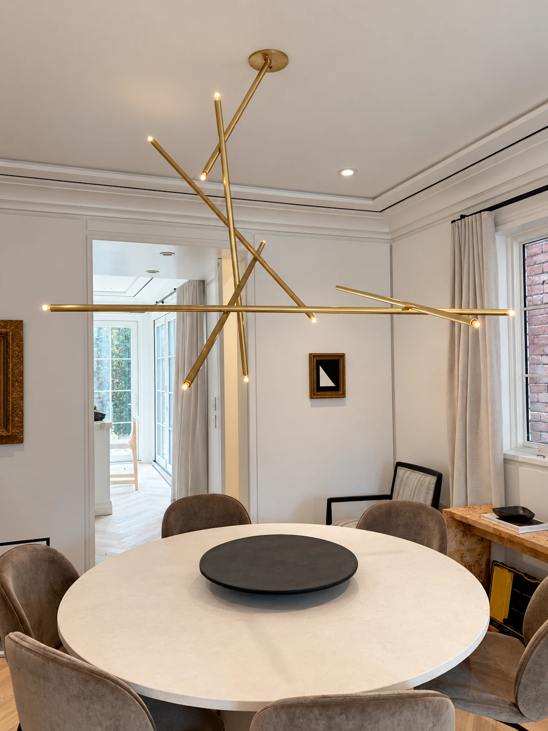 Sculptural branching brass chandelier above a round dining table
