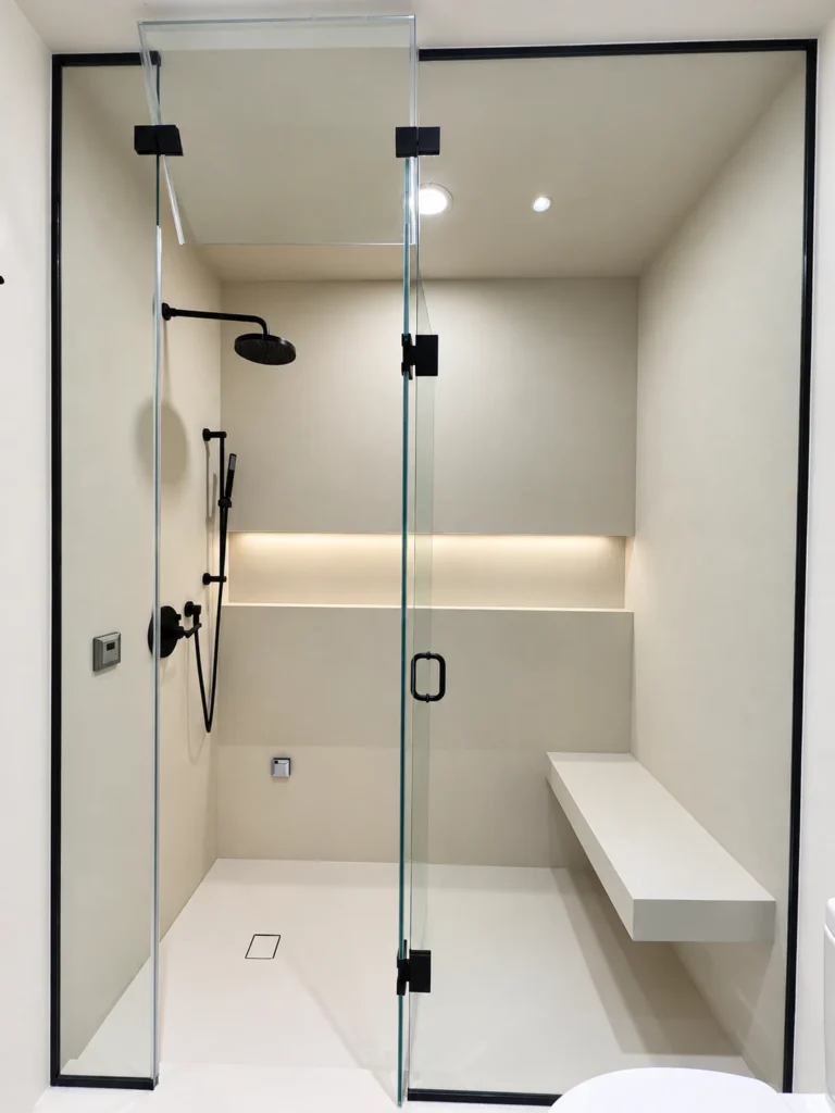 Glass-enclosed shower with recessed ceiling lighting, an illuminated wall niche and a built-in bench