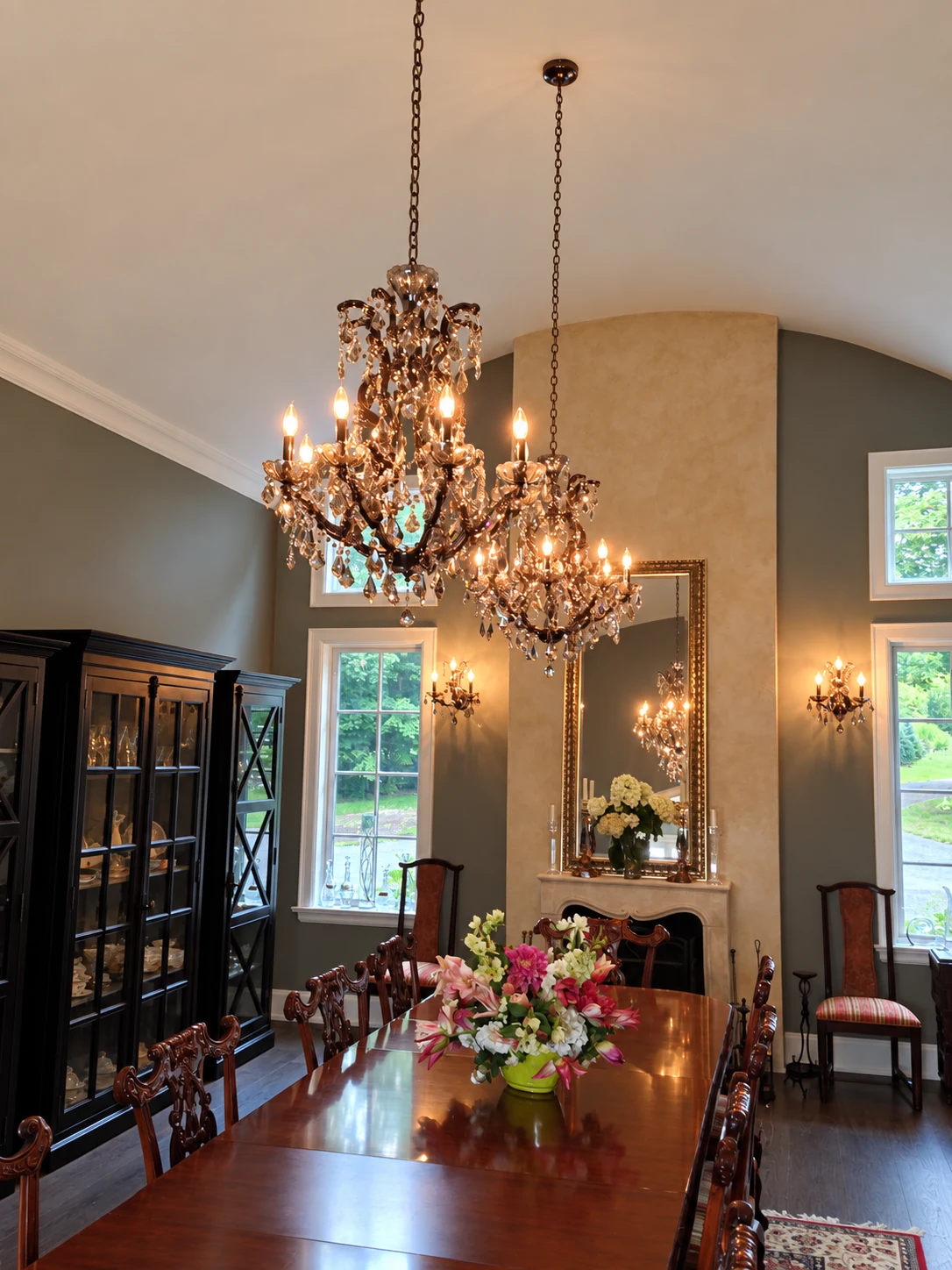Two crystal chandeliers and matching wall sconces illuminating a formal dining room