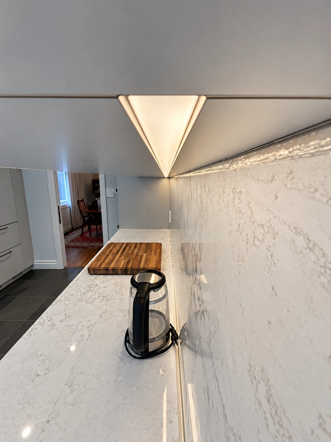 Close perspective along an illuminated triangular LED channel beneath kitchen cabinets